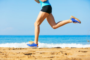 Sporty blonde woman in sportswear jogging on a sunny beach